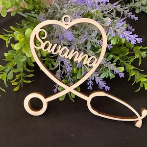 May include: Wooden heart-shaped ornament with a stethoscope design and the name "Savannah" written inside the heart.