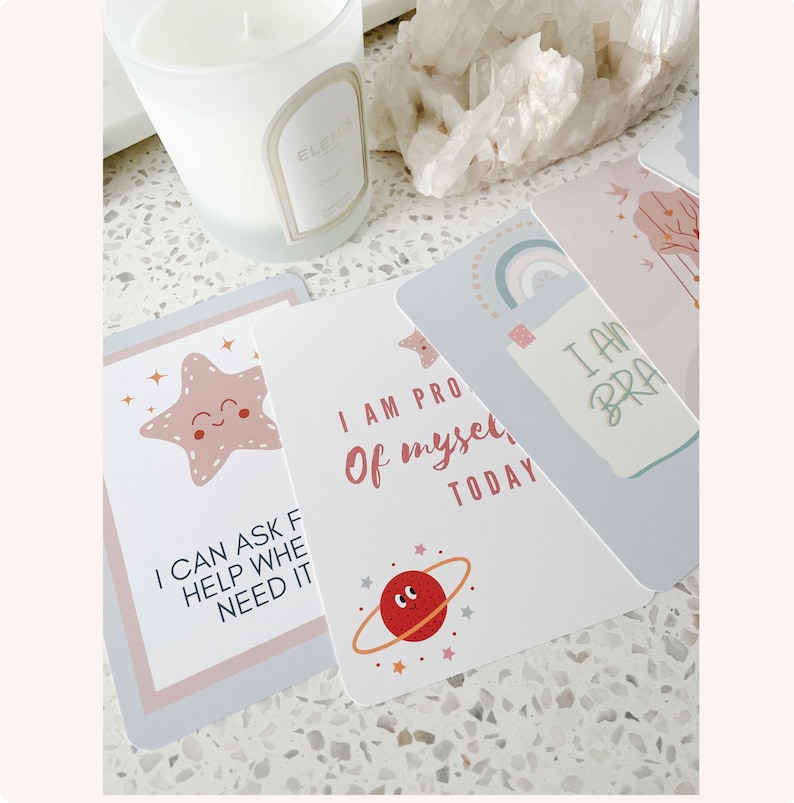 Puede incluir: Cuatro tarjetas de afirmaci&oacute;n con colores pastel e ilustraciones. Las tarjetas muestran el texto "Puedo pedir ayuda cuando la necesito", "Estoy orgulloso de m&iacute; mismo hoy", "Soy valiente" y una estrella de mar rosa con una cara feliz.