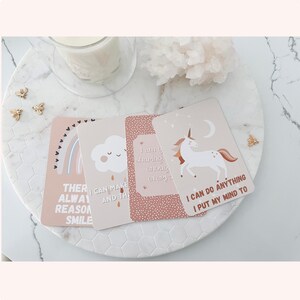 Puede incluir: Cuatro tarjetas de afirmaci&oacute;n con mensajes positivos e ilustraciones. Las tarjetas son rosas y beige con texto marr&oacute;n. Los mensajes son "Siempre hay una raz&oacute;n para sonre&iacute;r", "Puedo hacer y el", "Estoy compartiendo lo suficiente para todos", y "Puedo hacer cualquier cosa que me proponga".