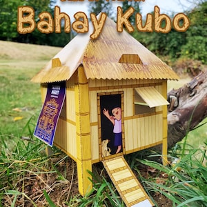 May include: A miniature, build-it-yourself Bahay Kubo model. The model features a bamboo-style structure with a thatched roof, a small ramp, and a figure waving from the doorway. The text "Build-It-Yourself Bahay Kubo" is displayed above the model.