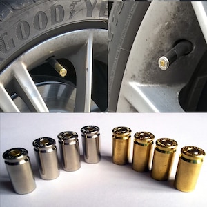 May include: A set of eight tyre valve stem caps made from bullet casings.  Four are gold and four are silver.  The caps are arranged in a semi-circle on a white surface.