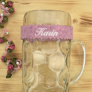 Könnte beinhalten: Ein klares Glasbierkrug mit einem rosa Filzband, auf dem "Karin" steht, um den oberen Rand.
