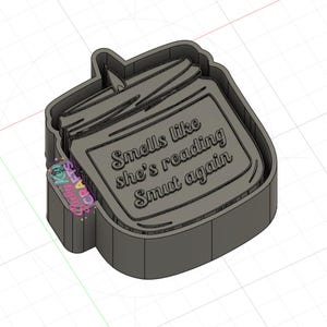 May include: A gray, jar-shaped cookie cutter with the text "Smells like she's reading Smut again." The cutter has a lid and a label area for the text. The design is a 3D rendering.