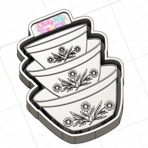 Op de afbeelding: Een 3D-gepresenteerde koekjesvorm met drie op elkaar gestapelde mengkommen. Elke kom is wit met een zwart bloemmotief. De uitsteker heeft een grijze omtrek en de tekst "Sticky Key Crafts" is zichtbaar.