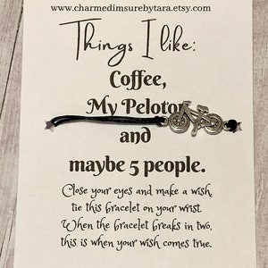 May include: A white card with black text that reads "Things I like: Coffee, My Peloton and maybe 5 people."  The card also includes instructions for a wish bracelet: "Close your eyes and make a wish tie this bracelet on your wrist. When the bracelet breaks in two, this is when your wish comes true."