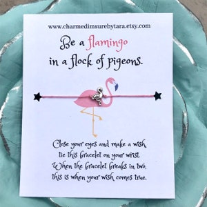 May include: Pink flamingo wish bracelet with a silver charm. The card reads "Be a flamingo in a flock of pigeons. Close your eyes and make a wish, tie this bracelet on your wrist. When the bracelet breaks in two, this is when your wish comes true."
