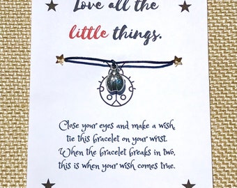 May include: A blue string bracelet with a silver ladybug charm. The card reads "Love all the little things. Close your eyes and make a wish tie this bracelet on your wrist. When the bracelet breaks in two, this is when your wish comes true."