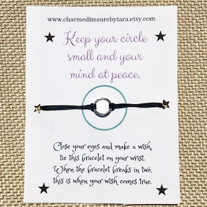 May include: A black string bracelet with a silver ring charm and gold star charms. The card reads "Keep your circle small and your mind at peace." and "Close your eyes and make a wish, tie this bracelet on your wrist. When the bracelet breaks in two, this is when your wish comes true."