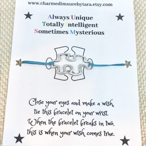May include: A silver puzzle piece charm bracelet on a blue cord. The card reads "Always Unique, Totally Intelligent, Sometimes Mysterious." Text below says to make a wish when tying the bracelet. The wish comes true when the bracelet breaks.
