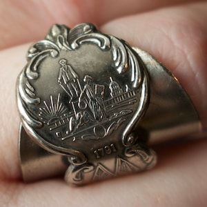 May include: Silver ring with a detailed design featuring a building and figures. The ring has a date of 1791 engraved on it.