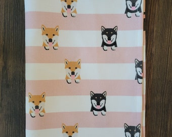 May include: Pink and white striped fabric with a repeating pattern of black and brown Shiba Inu dogs. The dogs are facing forward with their tongues sticking out.