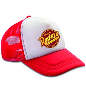 May include: A red and white trucker hat with the "Rust-eze Bumper Ointment" logo. The hat has a red peak and mesh back, with a white front panel displaying the logo in yellow and red.