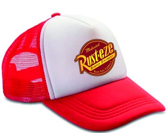 May include: Red and white trucker hat featuring the "Rust-eze Bumper Ointment" logo. The hat has a red brim and mesh back, with a white front panel displaying the logo in yellow and red.