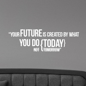 May include: A gray wall with a white quote that reads: "YOUR FUTURE IS CREATED BY WHAT YOU DO {TODAY} NOT TOMORROW." A gray sofa with a tufted back and a pillow is in the foreground.