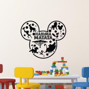 Può includere: Adesivo da parete in silhouette nera e bianca a forma di orecchie di Topolino con le parole "Hakuna Matata" e vari personaggi del film Il Re Leone.