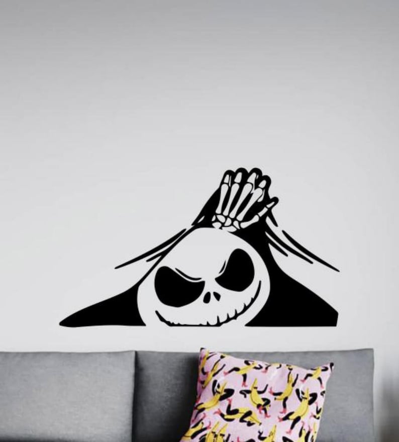 May include: Black and white vinyl decal of Jack Skellington from The Nightmare Before Christmas peeking out from behind a wall. The decal features Jack's signature grin and skeletal hand.
