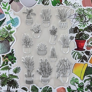 May include: A sheet of clear stamps featuring various potted plants and succulents. The stamps are arranged in a grid pattern on a white background. The stamps are perfect for adding a touch of greenery to your crafting projects.