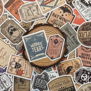 May include: A collection of vintage-style potion bottle labels with various designs and text, including "Mermaid Tears", "Spider Web", "Death Potion", "Scale of Dragon", "Magick Potion", and "Bat Wings".