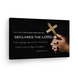May include: A black canvas print with a gold cross and a white text overlay. The text reads "FOR I KNOW THE PLANS I HAVE FOR YOU DECLARES THE LORD, PLANS TO prosper you AND NOT TO HARM YOU, PLANS TO GIVE YOU hope AND a future. JEREMIAH 29:11"