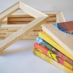 May include: A stack of five stretched canvases with different colorful paintings on them. The canvases are stacked on top of each other.  A pile of wooden canvas frames are in the background.  The text "Smile Art Design" is visible on the canvases.