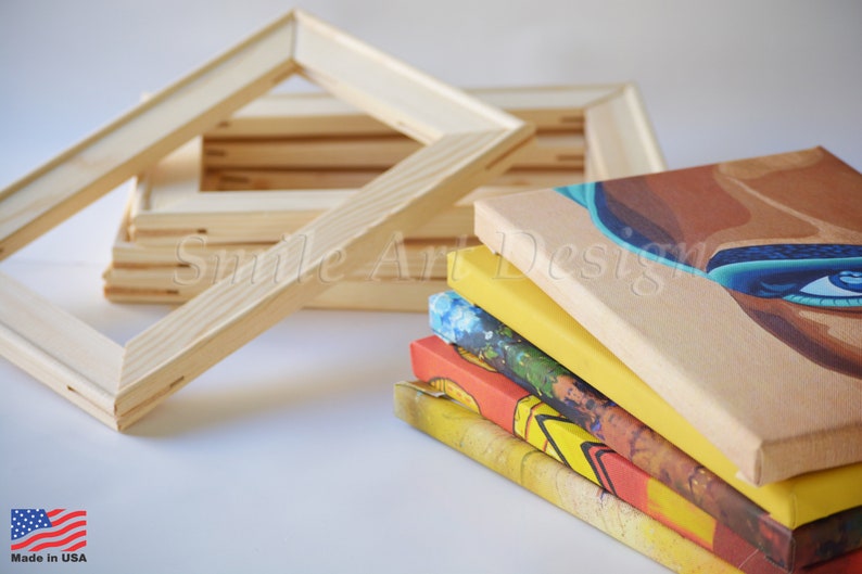 May include: A stack of five stretched canvases with different colorful paintings on them. The canvases are stacked on top of each other.  A pile of wooden canvas frames are in the background.  The text "Smile Art Design" is visible on the canvases.