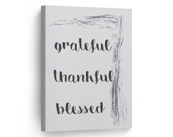 May include: A gray canvas print with a gray brushstroke design. The words "grateful", "thankful", and "blessed" are written in black cursive font.