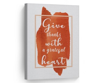 May include: A watercolor painting with a quote in a white frame. The quote reads "Give thanks with a grateful heart".