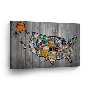 May include: A map of the United States of America made from vintage license plates. The map is on a gray wood background. Each state is represented by a license plate with the state name and abbreviation. The license plates are in various colors and designs.