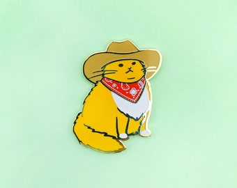 May include: A yellow cat wearing a red bandana and a brown cowboy hat. The cat is sitting with its legs crossed and its tail curled around its body.