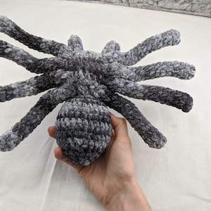 K&ouml;nnte beinhalten: Ein geh&auml;keltes graues und schwarzes Spinnenspielzeug mit einer flauschigen Textur.