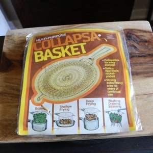 May include: A multi-purpose Collapsa Basket in its original packaging, featuring a wire mesh design and a handle. The packaging is brown, yellow, and orange, with text indicating its uses for boiling, frying, and straining.