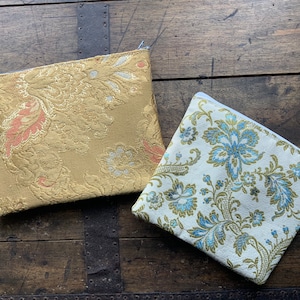 Trousse de maquillage. Beaux tissus d'ameublement en soie. Doublé d'un cuir synthétique à l'intérieur. Sac doré 20cm sur 15cm. Bleu Floral 17cm par 15cm.