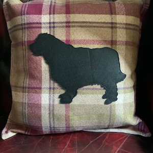 Può includere: Un cuscino decorativo con un motivo a quadri in tonalità di marrone, rosa e verde. Il cuscino presenta una silhouette di cane in feltro nero.