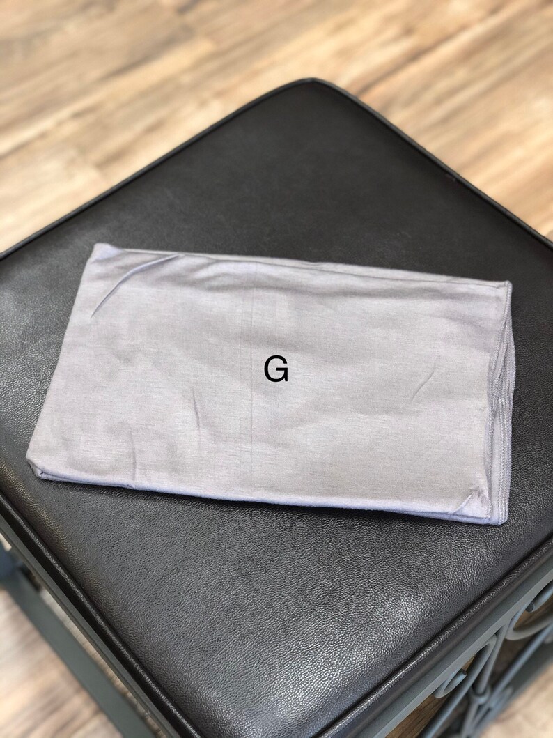 Puede incluir: Una diadema gris con la letra "G" impresa en ella.