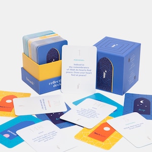 May include: A reflection deck with a blue and yellow box, and a blue cube-shaped box. The deck cards are white with blue borders and text. Some cards are scattered around the boxes. The text on the cards includes questions and the word "personal".