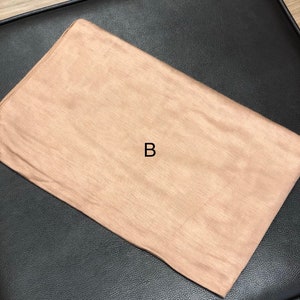 Puede incluir: Un rect&aacute;ngulo de tela marr&oacute;n claro con la letra "B" en el centro.