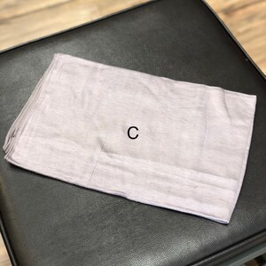 Puede incluir: Un rect&aacute;ngulo de tela gris claro con la letra "C" impresa en negro en el centro.