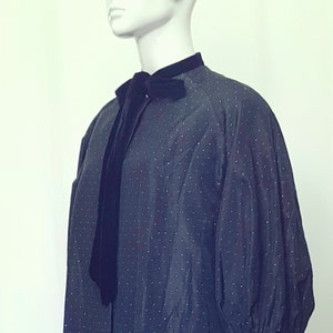 Pode incluir: Um vestido preto de bolinhas com um laço de veludo e um bracelete preto.