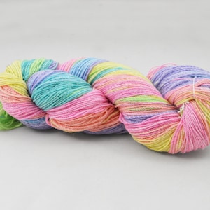 Może przedstawiać: Motka kolorowej włóczki w odcieniach różowego, zielonego, żółtego i fioletowego. Włóczka jest skręcona i spleciona, tworząc wizualnie atrakcyjny obraz.