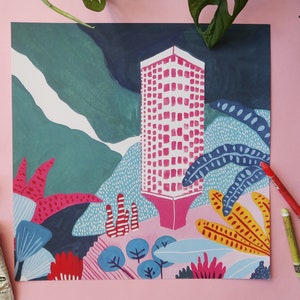 Könnte beinhalten: Ein abstraktes Gemälde mit einem hohen, rosafarbenen Gebäude mit einem Rastermuster, vor dem Hintergrund türkisfarbener und dunkelblauer Berge und farbenfrohem Laub. Das Kunstwerk befindet sich auf einer rosa Oberfläche, mit Kunstbedarf wie Farbtuben und Pinseln.