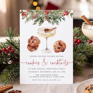 May include: A white rectangular invitation card featuring a watercolor illustration of pine branches, pinecones, and red berries at the top. Below are illustrations of a cocktail glass and chocolate chip cookies. Text reads: YOU'RE INVITED TO JOIN US FOR cookies & cocktails AT OUR ANNUAL CHRISTMAS PARTY SATURDAY, DECEMBER 10TH AT 7 PM THE ANDERSON HOME 520 WHITE PINE DRIVE, PORTLAND RSVP TO 555.555.5555 BY 12/1.