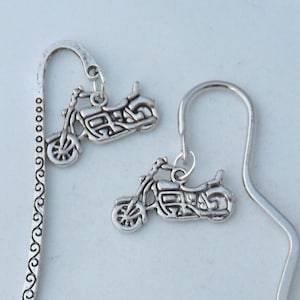 May include: Two silver motorcycle bookmark charms. One bookmark has a silver, decorative, curly design. The other bookmark has a simple, silver, wavy design.