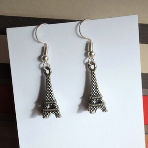 May include: Silver earrings with a small Eiffel Tower charm hanging from each earring.