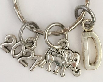May include: Silver keychain with a 2021 charm, an elephant charm, and a letter D charm.