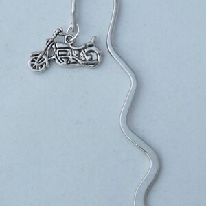 May include: Silver bookmark with a motorcycle charm. The bookmark is shaped like a wavy line.