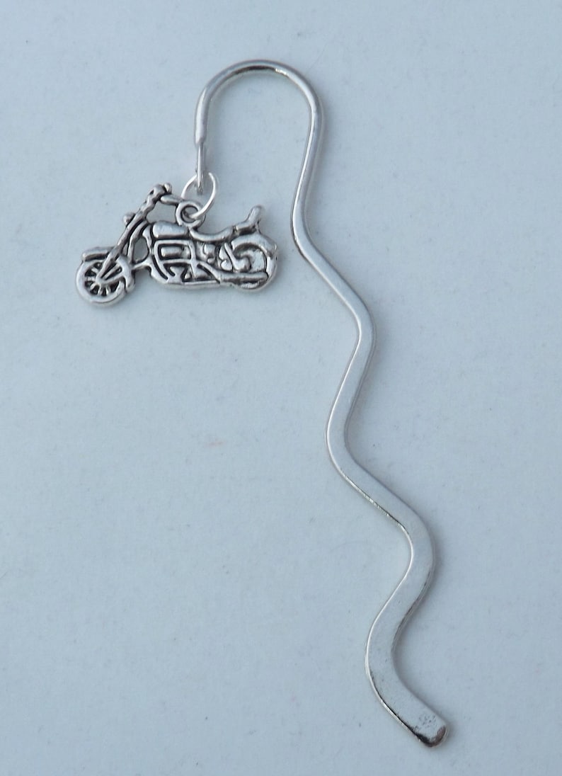 May include: Silver bookmark with a motorcycle charm. The bookmark is shaped like a wavy line.