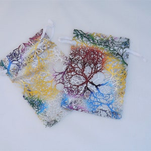 May include: Two small, white, mesh drawstring bags with colourful tree branch designs. The bags are made of sheer fabric with a white drawstring.