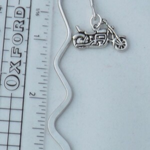 May include: Silver bookmark with a motorcycle charm. The bookmark is approximately 7.6 cm long and has a wavy design.