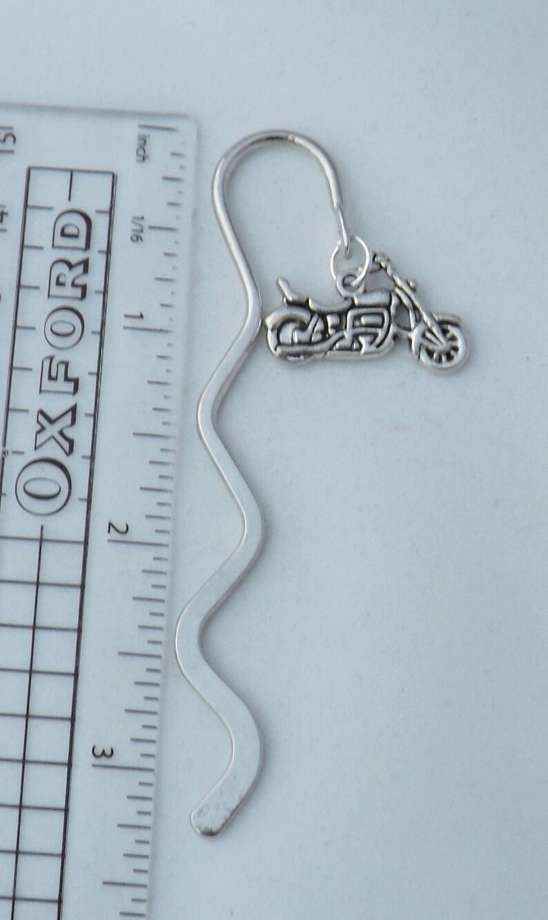 May include: Silver bookmark with a motorcycle charm. The bookmark is approximately 7.6 cm long and has a wavy design.