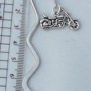 May include: Silver bookmark with a motorcycle charm. The bookmark is approximately 8 inches long and has a wavy design.